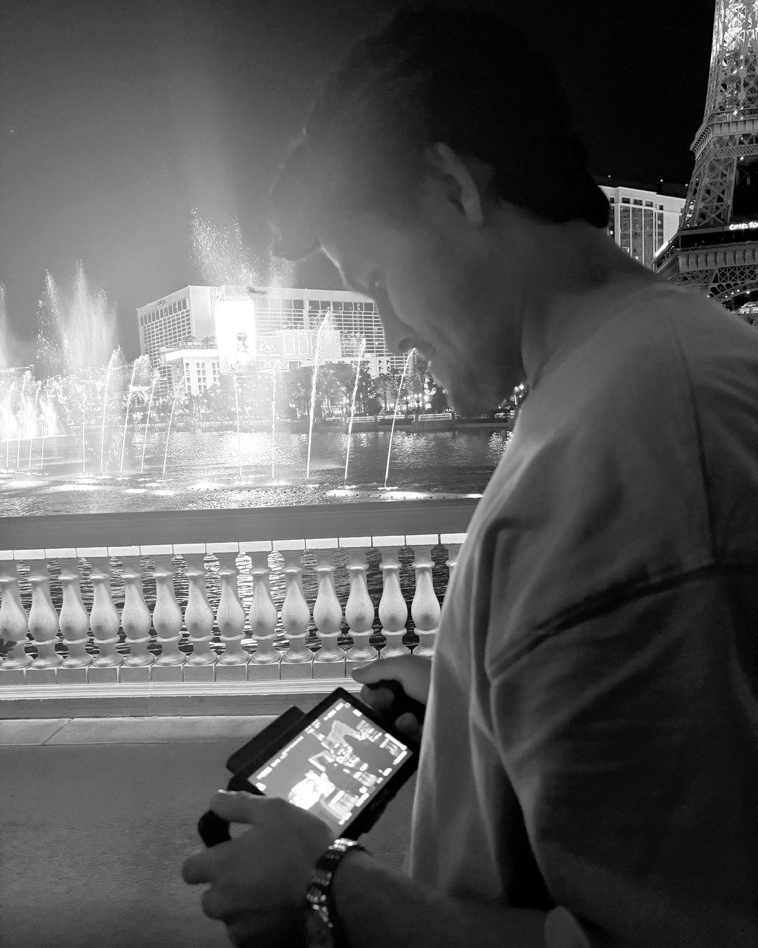 Cameron March on set at night, checking a monitor by the Bellagio fountains